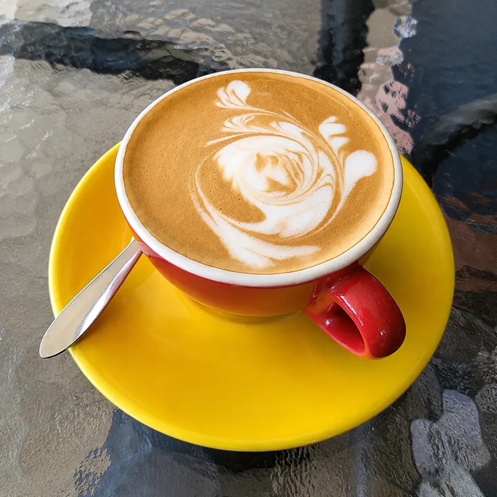 Coffee served in a red cup on a yellow saucer