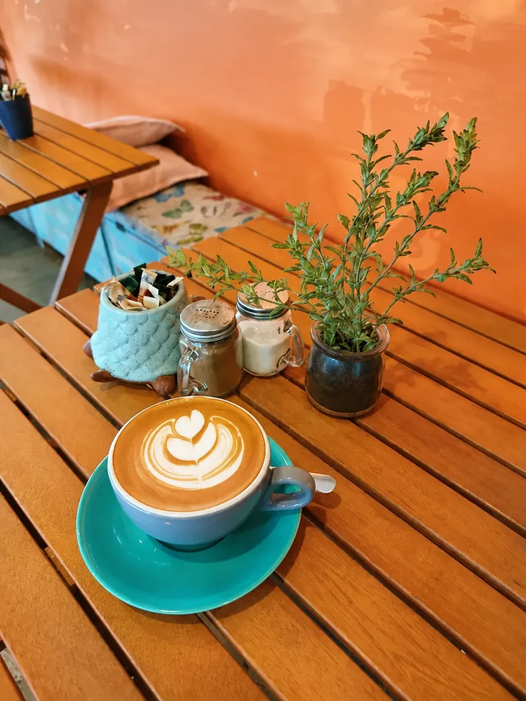 Latte on a wooden table with fresh greenery
