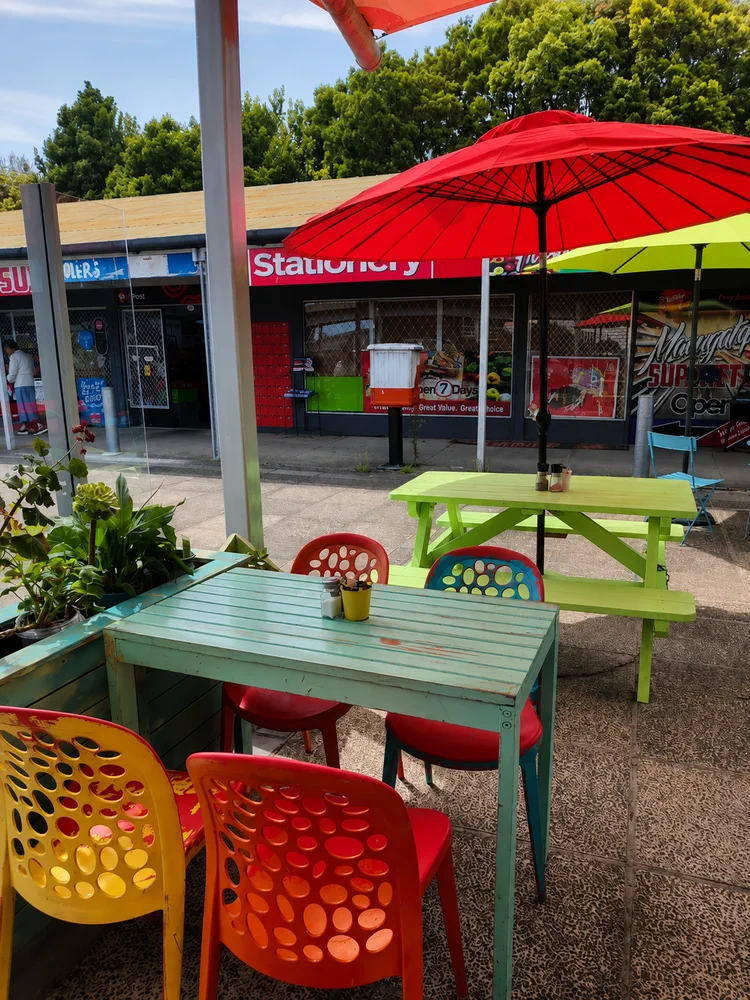 Bright outdoor tables and umbrellas outside Fat Cat Street Coffee