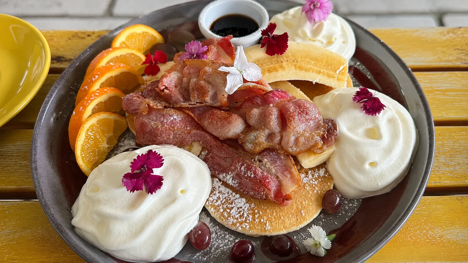 Pancakes served with bacon, banana, fruit and cream