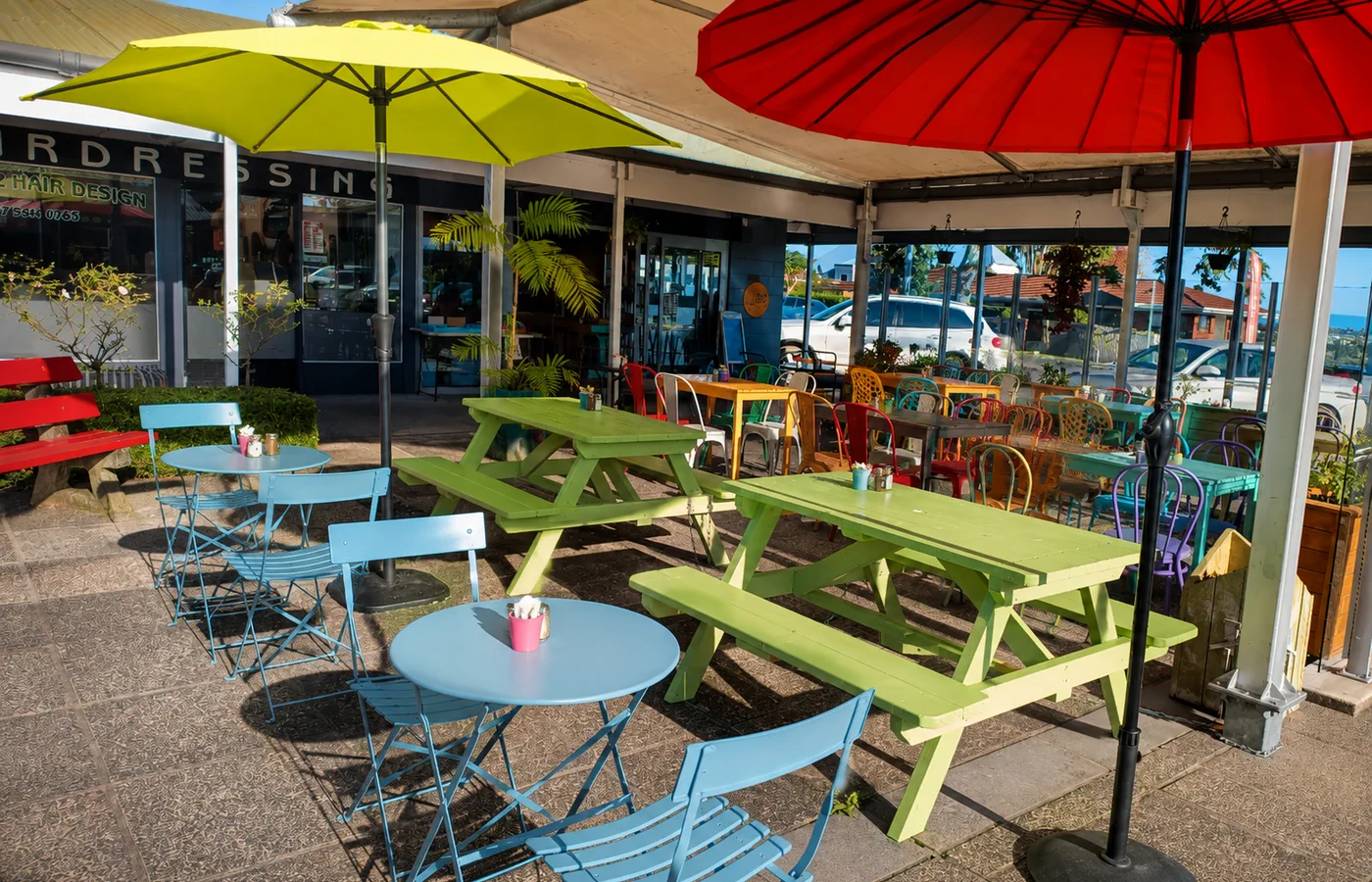 Colourful outdoor tables beneath bright umbrellas